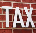 The word TAX on a brick wall